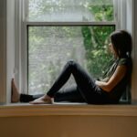 Donna in menopausa seduta vicino a una finestra soleggiata, momento di relax