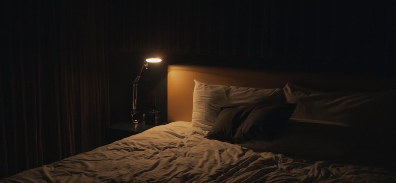 Comodino con lampada accesa in una camera da letto rilassante, routine serale per dormire meglio