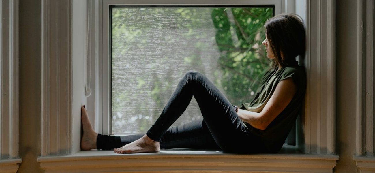 Donna in menopausa seduta vicino a una finestra soleggiata, momento di relax